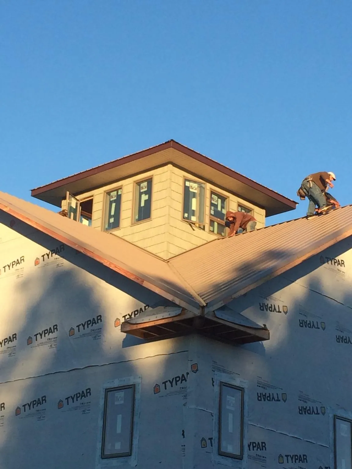 Roofers working around a rooftop cupola on a new metal roof at sunset — Roof Waterproofing in Middlebrook by Roofing Brothers
